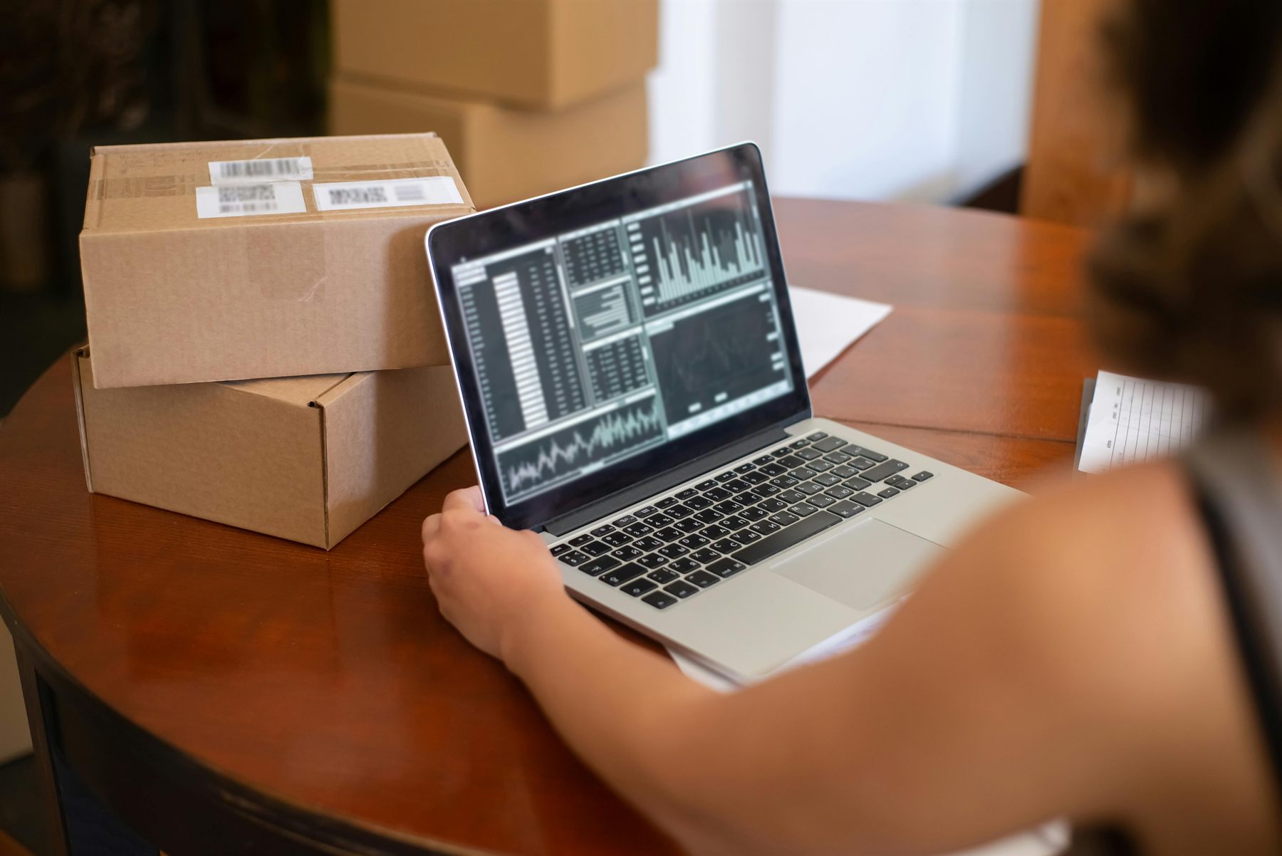 Laptop showing sales charts beside ecommerce shipping boxes